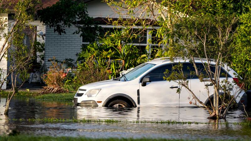 A car sits in high water in front of a home in the aftermath of hurricane Milton, Thursday,...